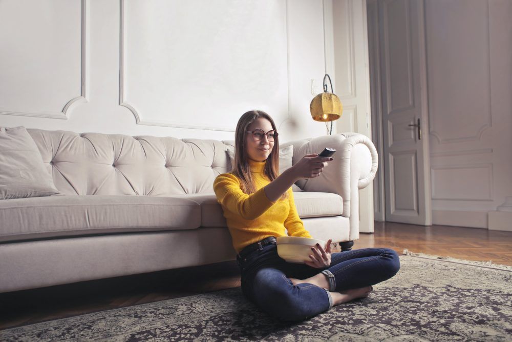 woman sitting on floor using remote control